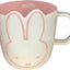 Taza de café con cara de Miffy blanca y rosa y garabatos de flores