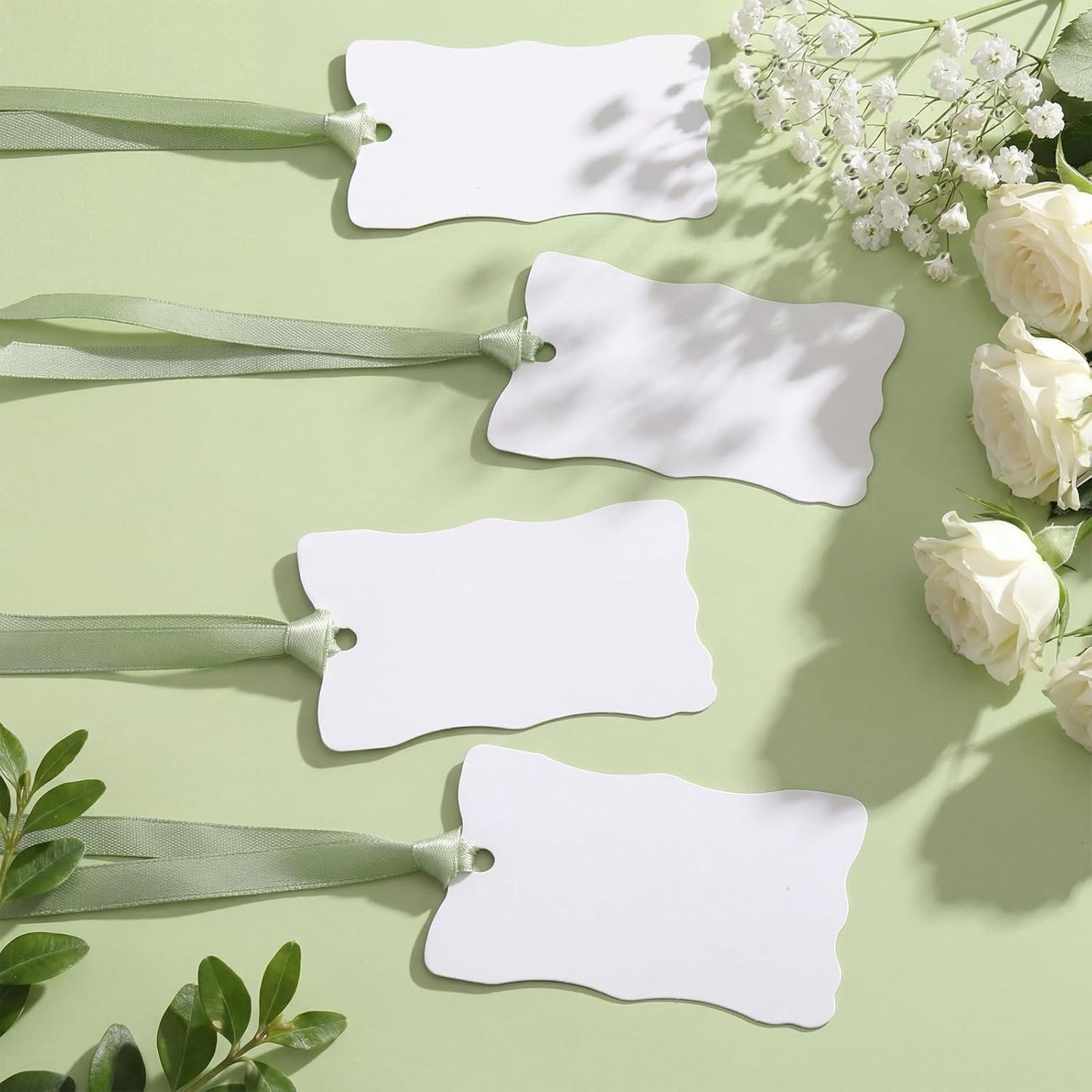 Tarjetas irregulares con borde ondulado para mesa de boda en blanco con cinta de satén